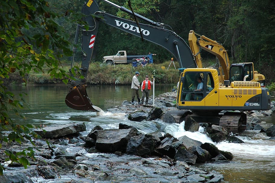 Yellow Volvo Excavator On Rocks Near River Beside People, - Excavator Hd Wallpaper Volvo - HD Wallpaper 