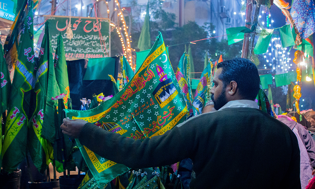 A Man Selects One Of The Flags With - Eid Milad Un Nabi Karachi - HD Wallpaper 